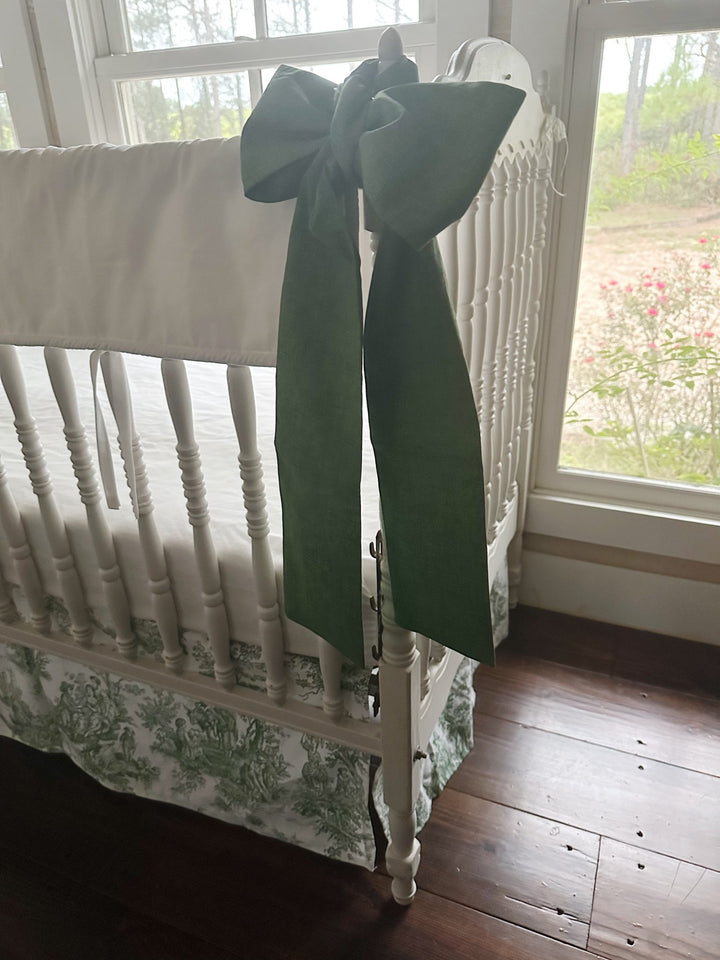 Cypress green bow and the white rail cover's tiny white ties seen from the side of the crib
