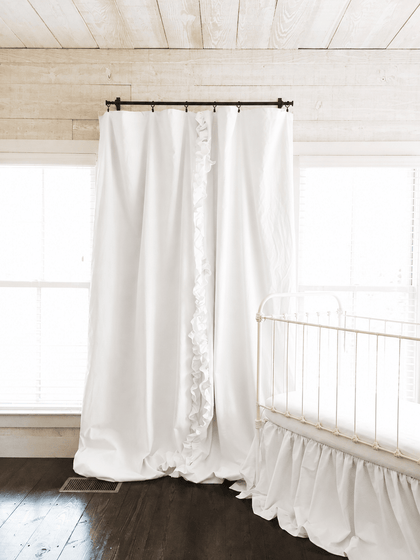 Full length white blackout curtains from rod to floor in a shiplap nursery with a white iron crib - High Cotton Textile