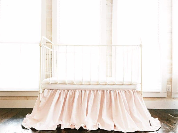 Baby pink ruffled crib skirt with a matching ruffle on all four sides and a 22-inch drop